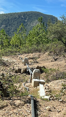     El Tablon Water project: New buttressed metal                                                                                                                                                       piping from water source to cistern (also shown is                                                                                                                                                    portions of the old flexible hose system which functioned                                                                                                                                                                        poorly in the gravity system).